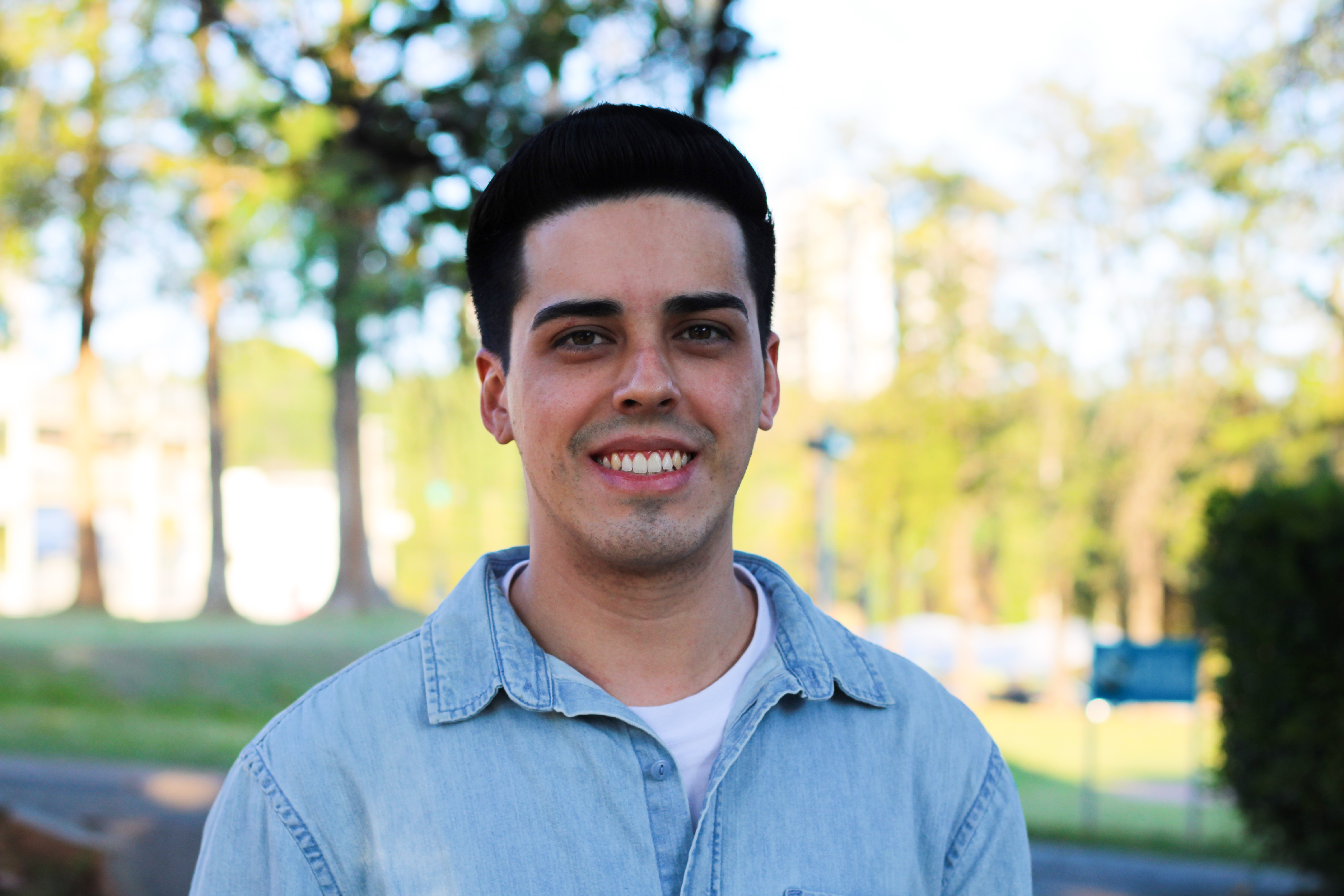 Foto de Danilo de Lima Ferreira, aluno de engenharia da computação.   Jovem com pele branca, cabelos curtos escuros, usa camisa azul sobre camiseta branca, posa sorridente.