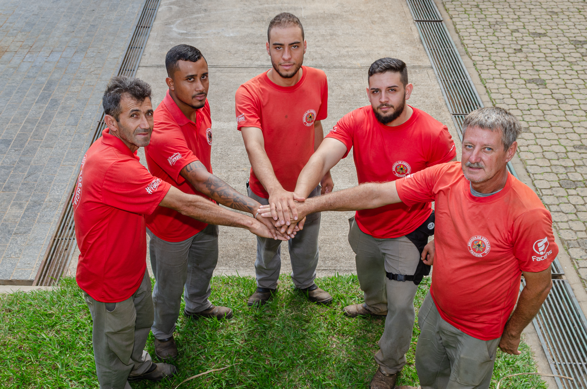 foto do alto. Ademar Felinto da Silva e mais cinco pessoas em pé formam um semicírculo e, tocam as mãos ao centro.