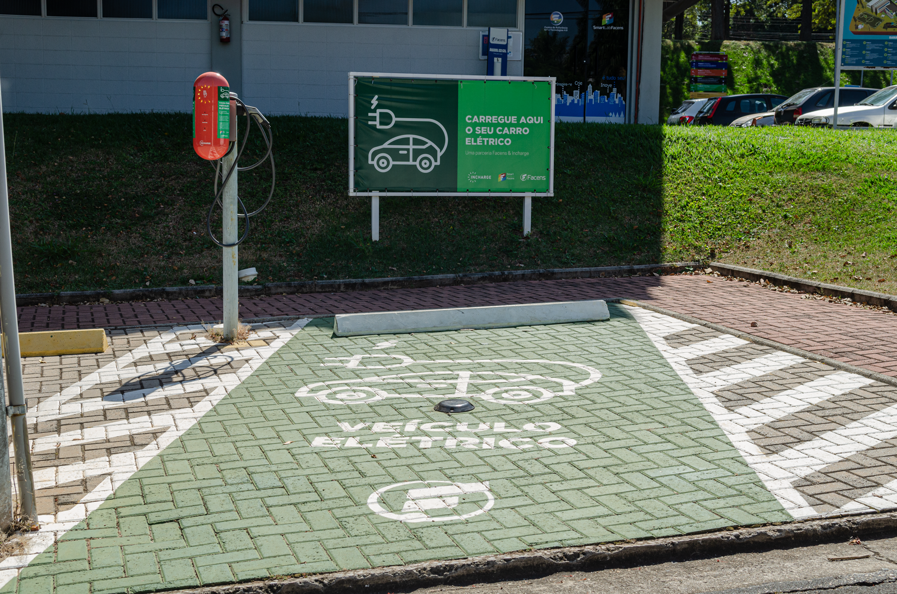 Foto: estacionamento. No chão demarcado lê-se: veículos elétricos e um carro desenhado ligado a um fio com tomada.